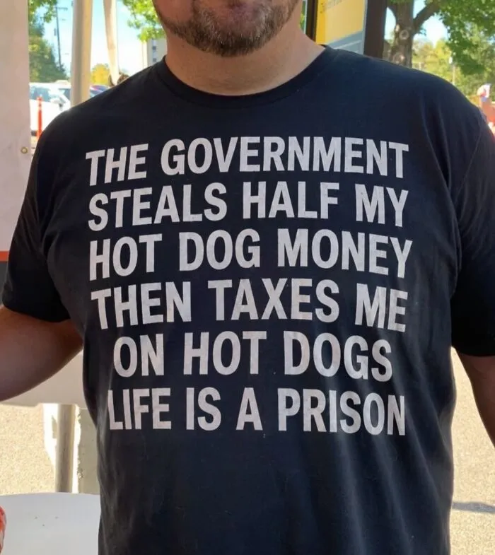 Man wearing a hilarious t-shirt with funny text about hot dogs and taxes.