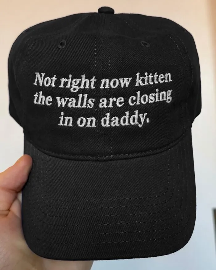 Black embroidered baseball hat featuring hilarious and unexpected text about the walls closing in