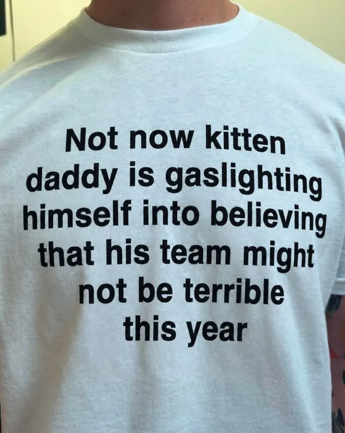A white t-shirt featuring funny printed text about gaslighting and sports teams.