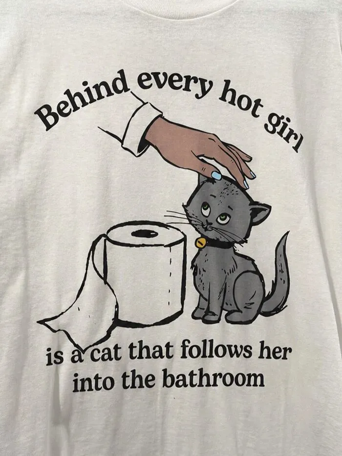 Hilarious t-shirt graphic showing a cat beside toilet paper with text about cats following owners to the bathroom.