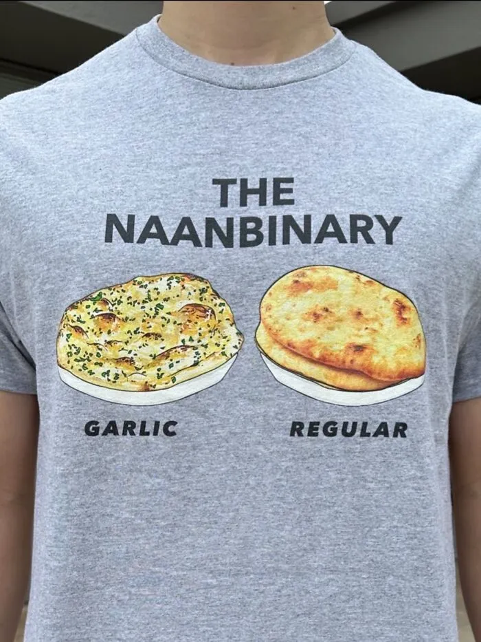 Person wearing a hilarious t-shirt with a pun about naan bread reading THE NAANBINARY.