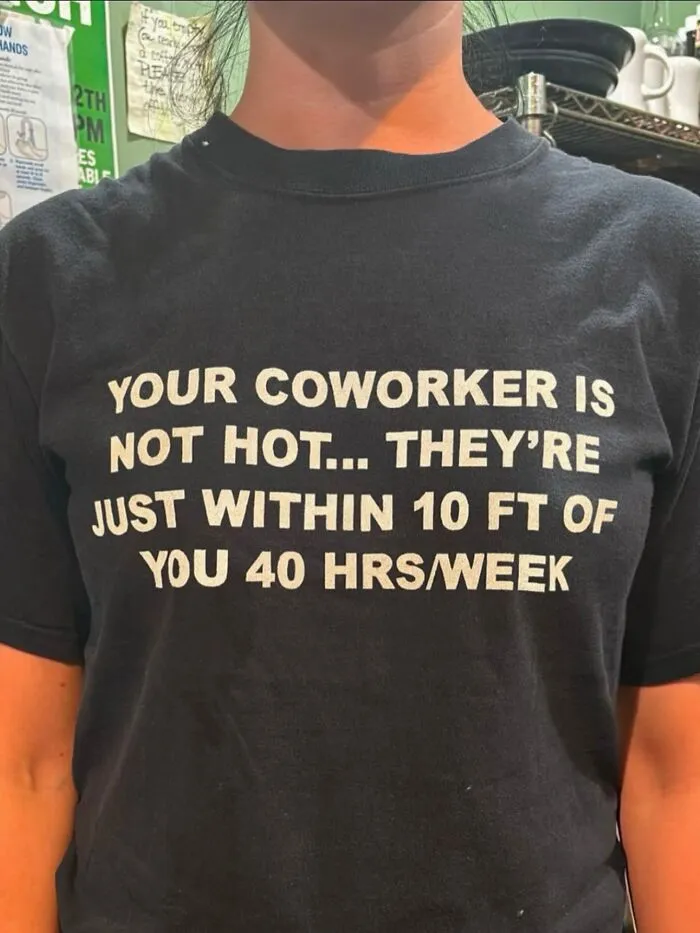 A person wearing a hilarious t-shirt with text about office romance and coworkers.
