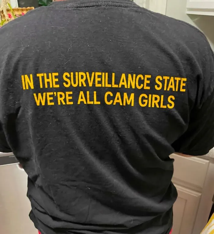 Person wearing a hilarious t-shirt with yellow text about the surveillance state.