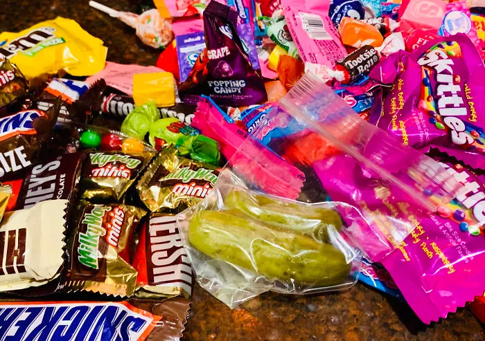 A large pile of Halloween candy featuring chocolate bars and Skittles