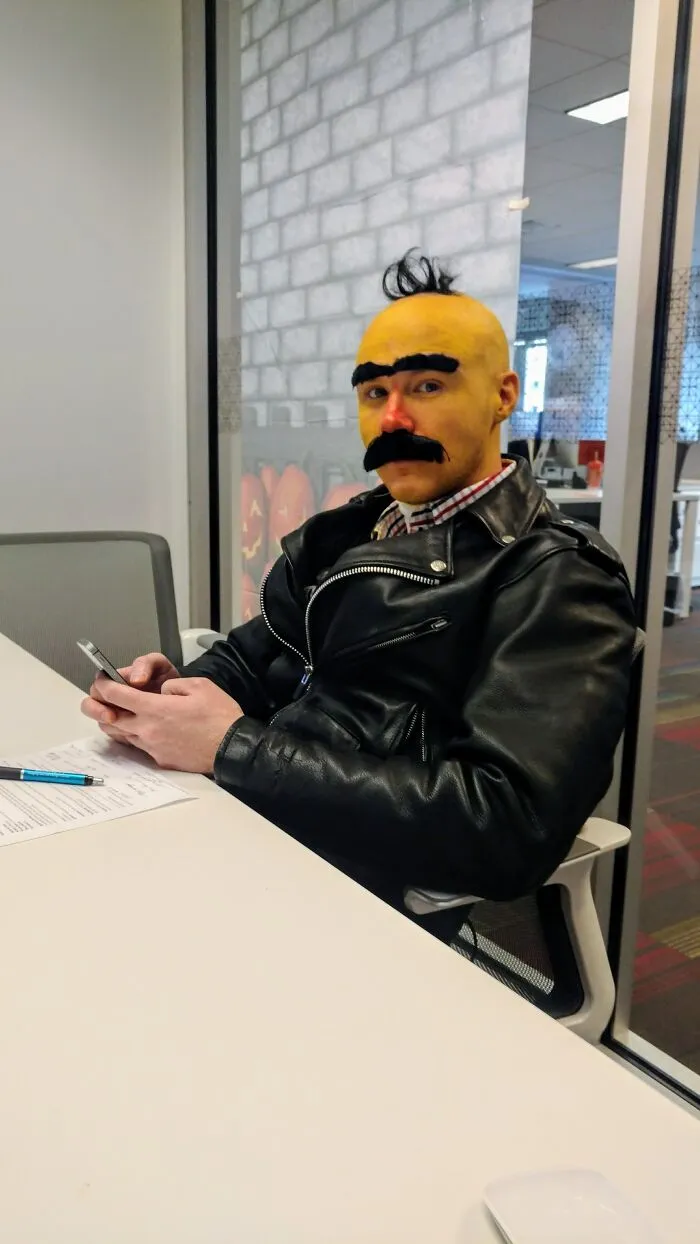 Man wearing a funny Bert Halloween costume sitting at an office desk.