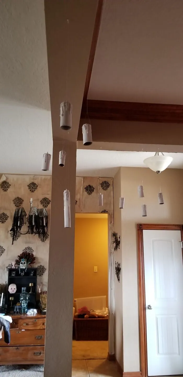 DIY floating candles made of cardboard rolls hung indoors for funny Halloween decor.