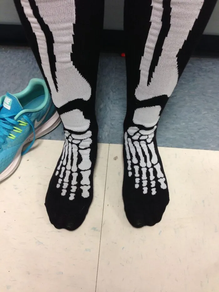 Close up of Halloween skeleton socks worn on the wrong feet