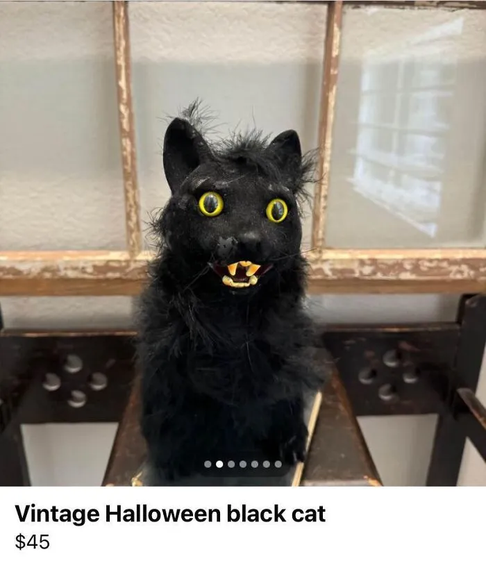A bizarre vintage Halloween black cat prop with wild yellow eyes and pointy teeth
