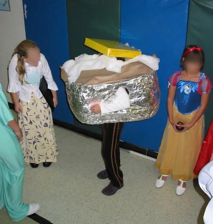 A child wearing a handmade foil baked potato costume standing next to friends