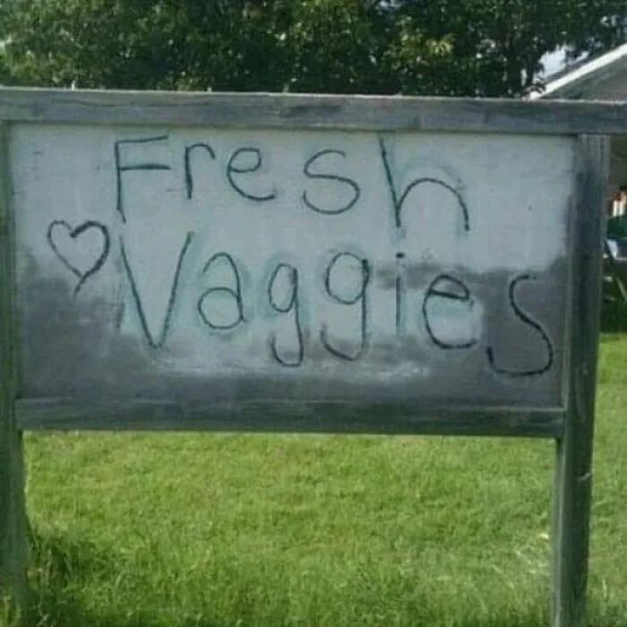 A wooden sign reading Fresh Vaggies with a heart, an example of funny spelling fails on a farm stand.