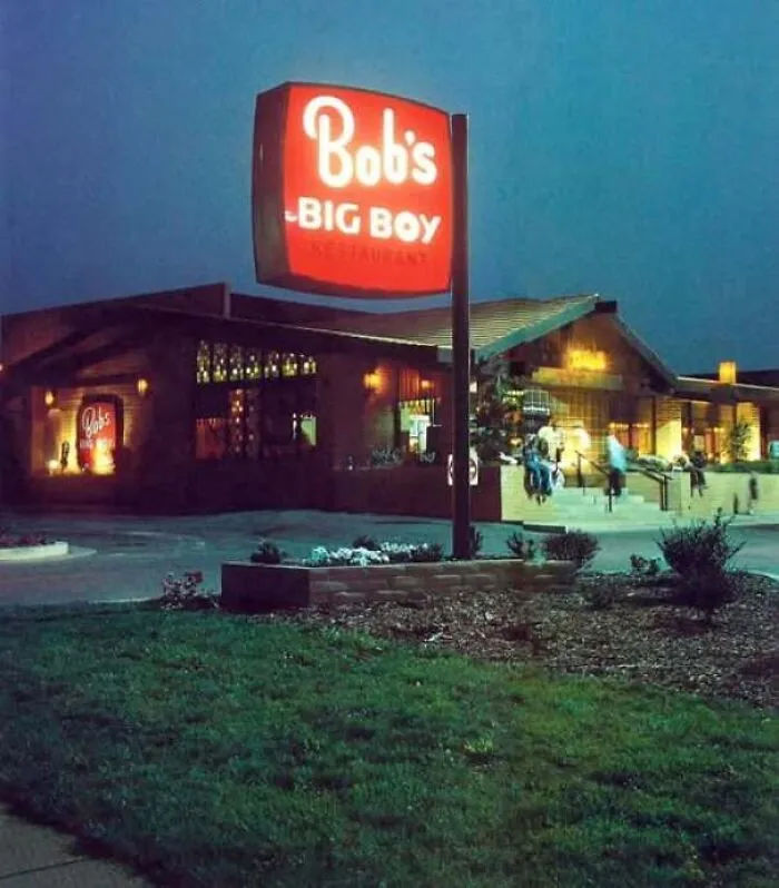 Retro exterior view of Bobs Big Boy restaurant lit up at dusk in vintage America.