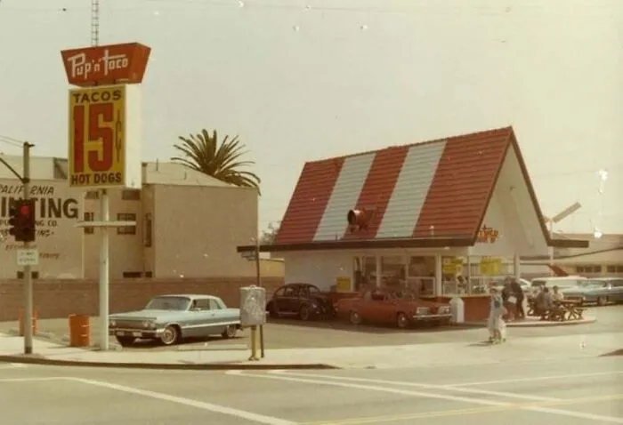 A vintage Pup 'N Taco fast-food restaurant drive-in showing vintage cars, from old photos of America.
