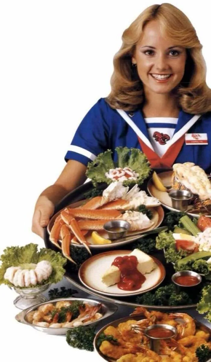 Vintage advertisement image showing a smiling waitress serving a seafood feast with crab legs and shrimp