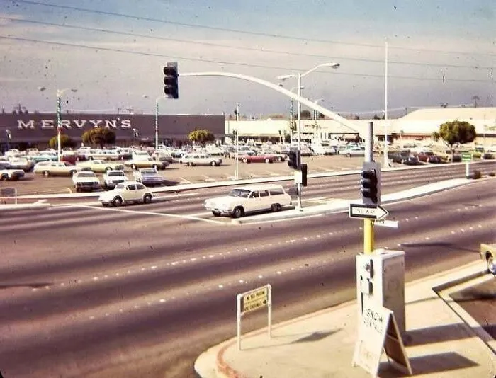 A vintage street scene with classic cars in an old photo of America outside a Mervyn's department store.