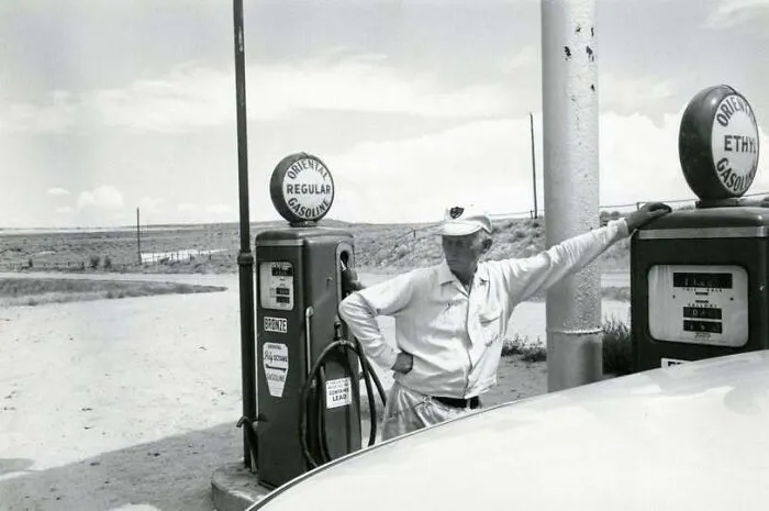 A gas station attendant posing by vintage fuel pumps featured in old photos of America.