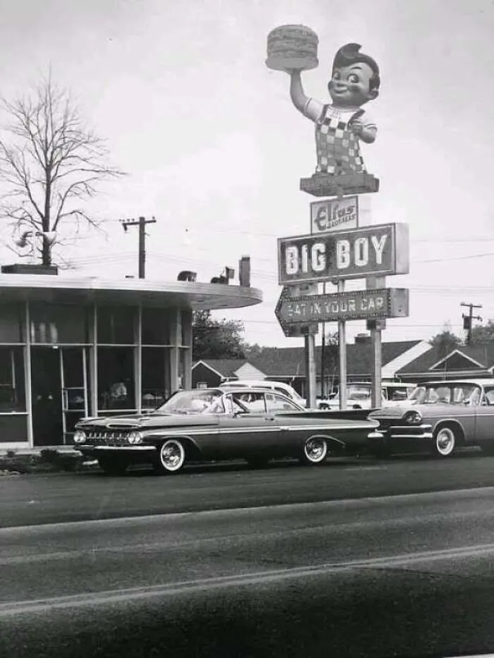 Black and white vintage photo of a Big Boy drive-in restaurant with vintage cars parked outside.
