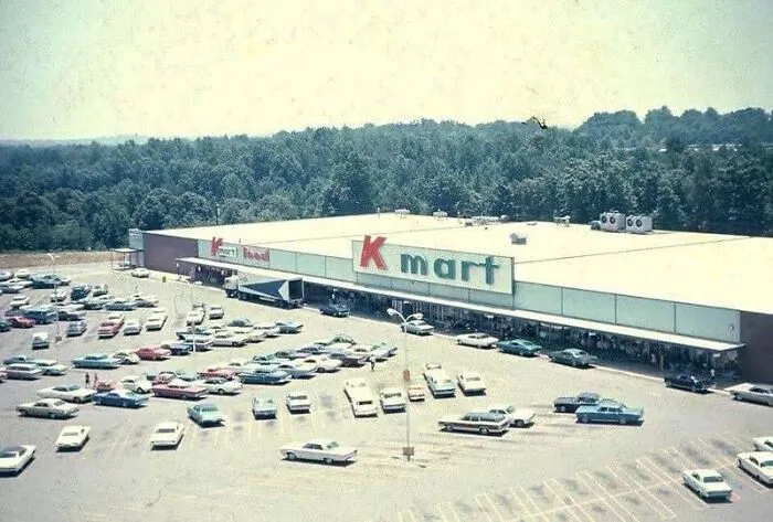 Aerial view old photo of a Kmart store and busy parking lot surrounded by trees in America.