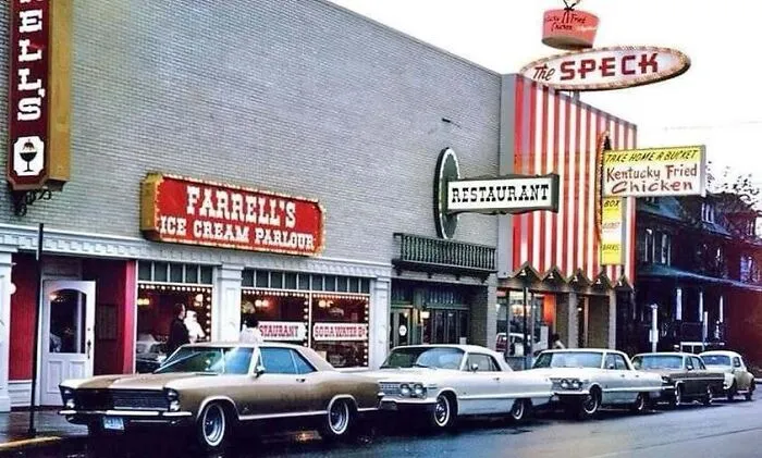 Street view featuring retro storefronts and classic cars parked outside in old photos of America.