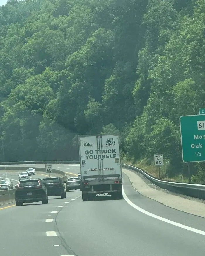 Semi-truck driving on the highway with the punny phrase GO TRUCK YOURSELF printed on the back doors