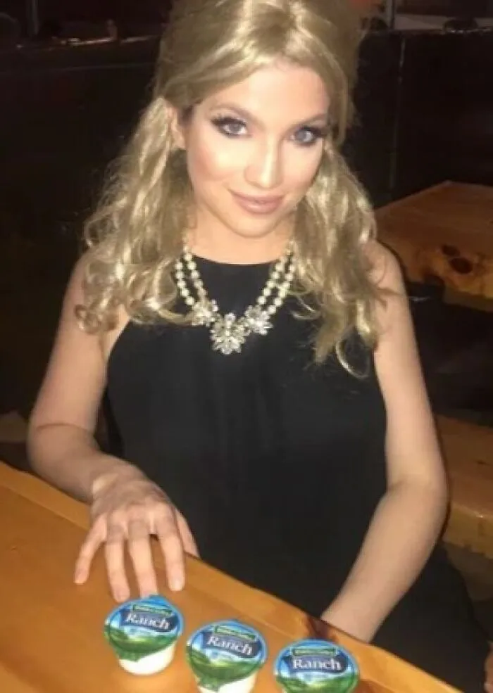 A blonde woman sitting at a table with ranch cups, serving as a cool Halloween costume idea.