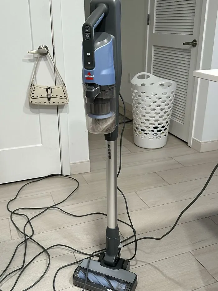 A Bissell stick vacuum standing on a wooden floor, popular on Big Deal Days.