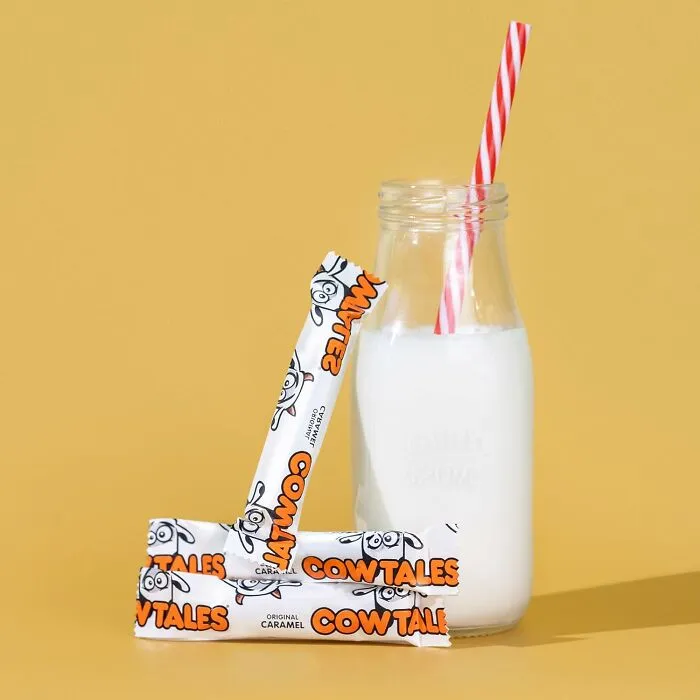 Cow Tales wrapped caramel candies leaning against a glass bottle of milk for Best Halloween Candies.