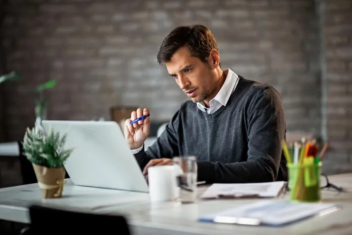 A confused man looking at his laptop screen at a desk, representing absurdly obvious lies online