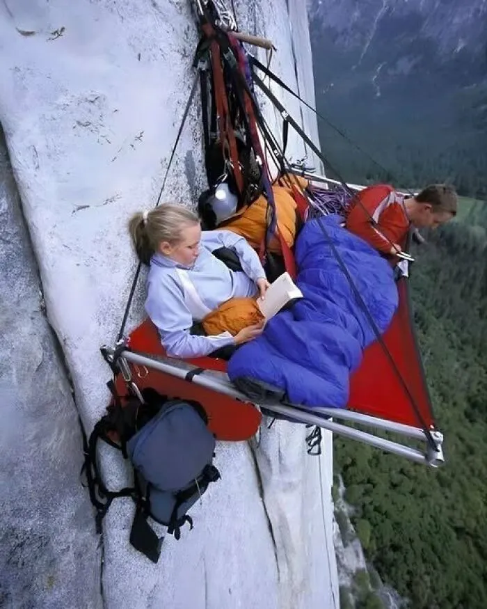 Entertaining and thrilling view of rock climbers resting in a portaledge suspended high on a cliff