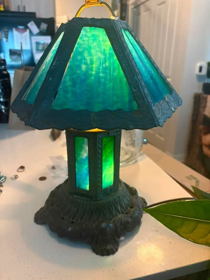 An ornate antique green stained glass lamp resting on a table, a rare thrift store find.