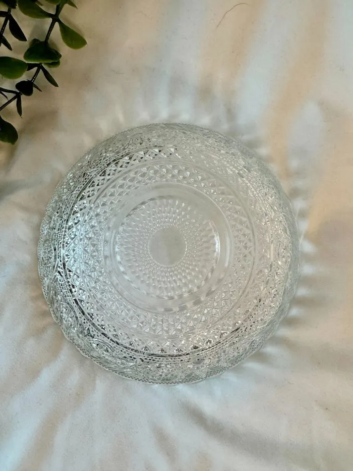 Clear glass bowl thrift store find with intricate patterns on white fabric