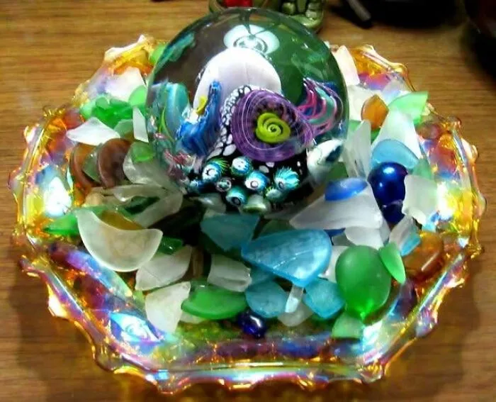 Colorful glass paperweight surrounded by sea glass pieces, displayed as a wonderful thrift find.