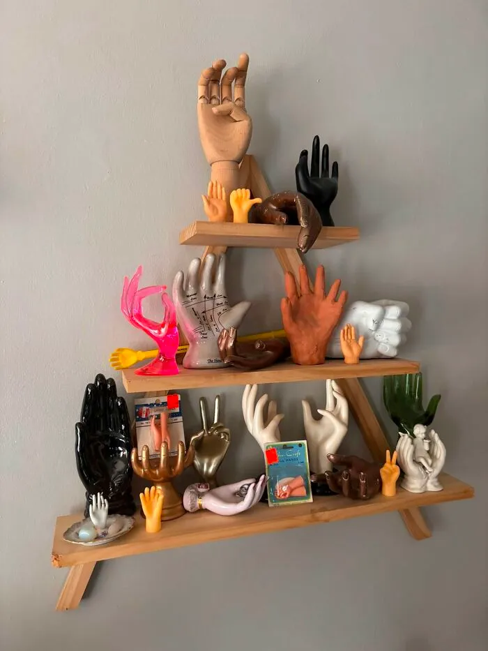 Shelves decorated with a collection of hand sculptures in various poses and colors, a creative thrift find