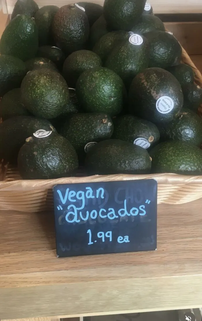 A basket of fruit with a price tag that misuses quotation marks around avocados.