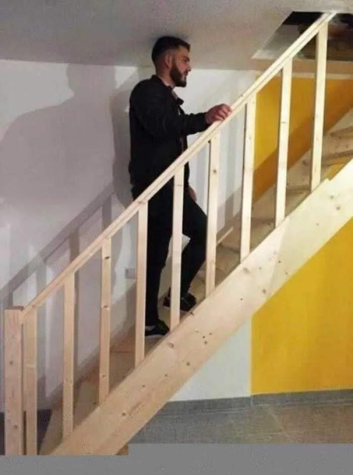 A man standing on stairs with no headroom, illustrating a home renovation design fail.