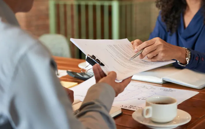 Two people reviewing legal paperwork on a table, illustrating legal battles in divorce stories.