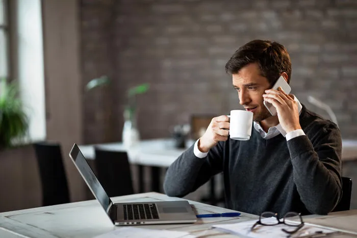 A parent talking on the phone while working, managing tasks related to helicopter parenting