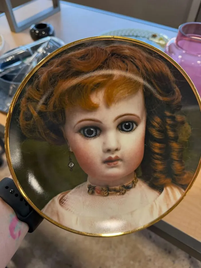 A decorative plate featuring a vintage doll face, one of many thrift finds.