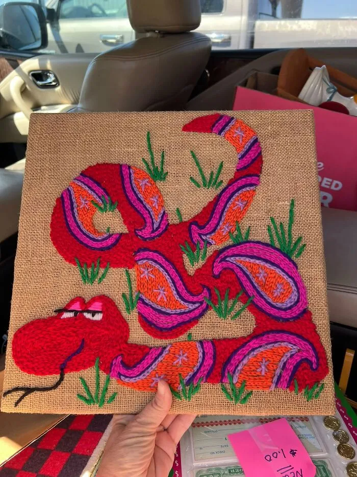 Colorful snake embroidery on burlap fabric displayed as a quirky thrift find.
