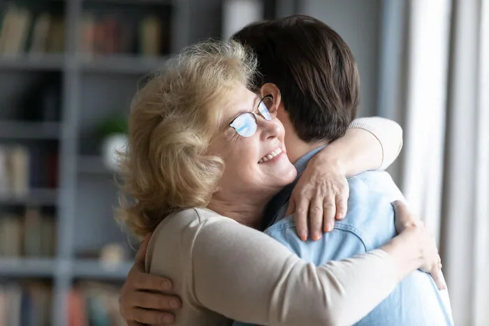 An overbearing mother hugging her adult son, representing helicopter parenting