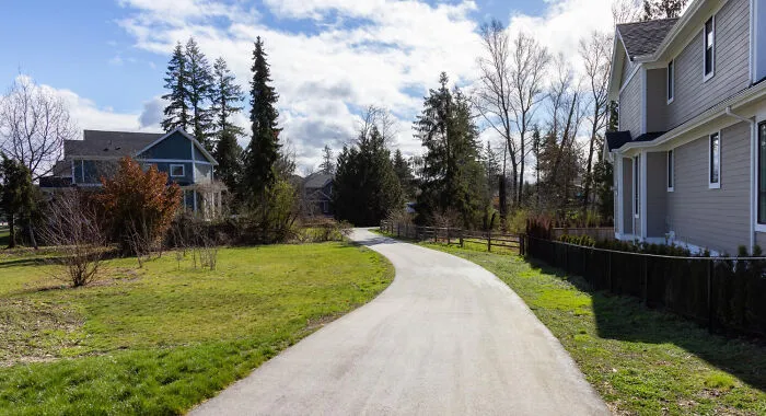 A paved neighborhood path surrounded by trees and houses, representing suburban safety and emergency tips.