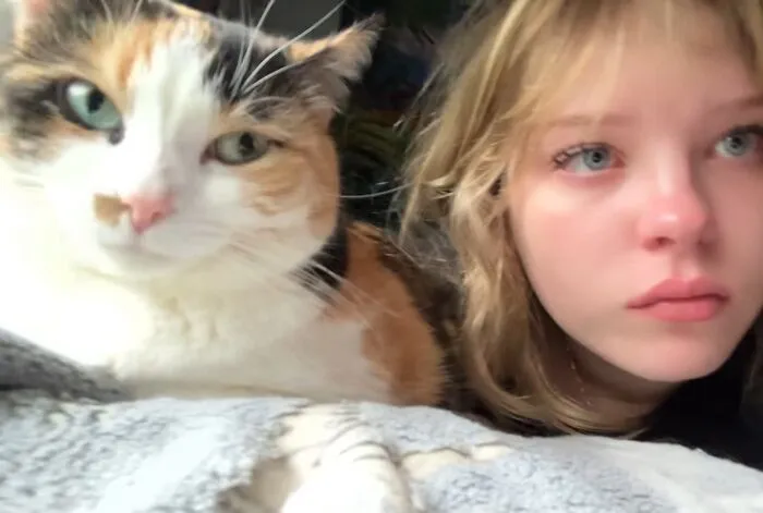 A teenage girl with light eyes and a calico cat, showing how much pets looked like their owners