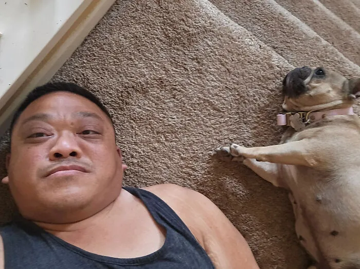 A man lying on the floor next to his look-alike pet dog