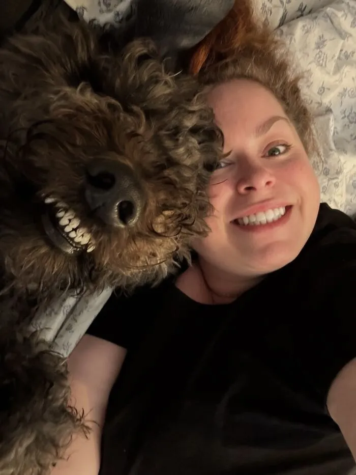 A woman and her fluffy dog showing matching wide-toothed smiles, showing pets look like owners