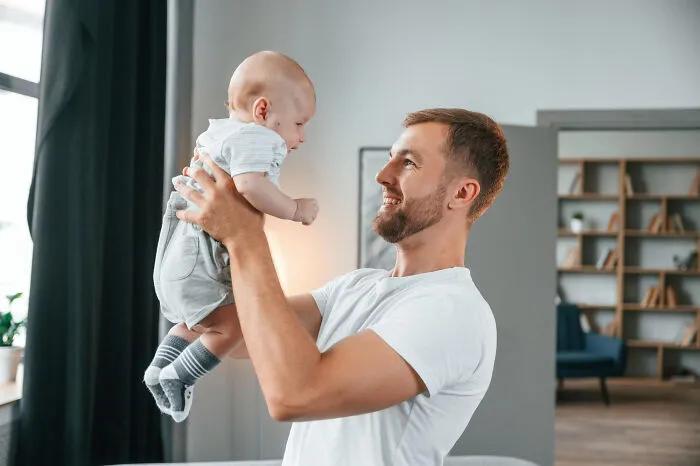 A happy father holding his baby high, a moment showing why people told partners questioning intelligence