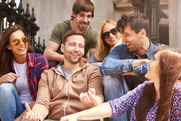 A group of young, cheerful friends hanging out together on steps, representing lifelong friendships.