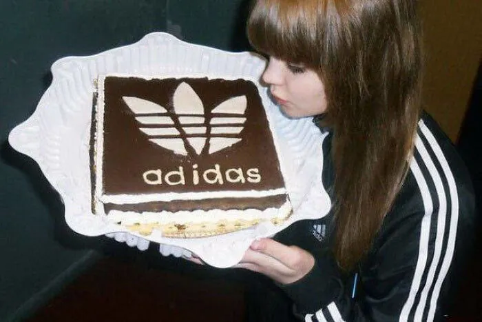 Girl posing with an Adidas-themed chocolate cake as an example of creative Slavic engineering.