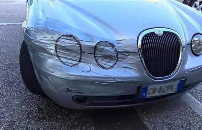 Car headlight repaired with duct tape and marker drawings depicting funny Slavic engineering.
