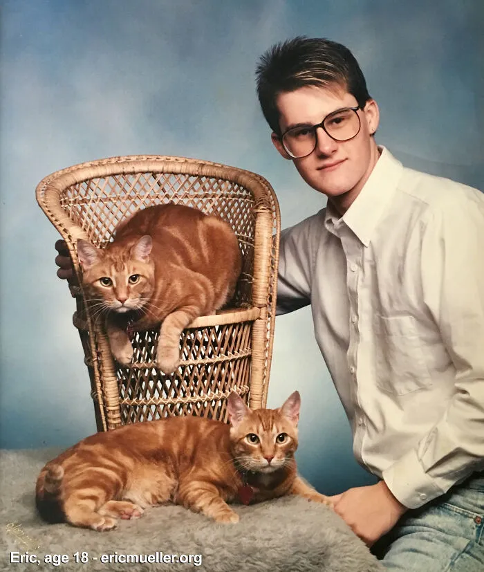 A young man posing with two ginger cats on a wicker chair for a funny family photo.