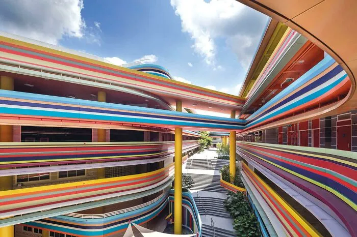 Exterior view of a strange colorful building with curved multicolored stripes and yellow pillars
