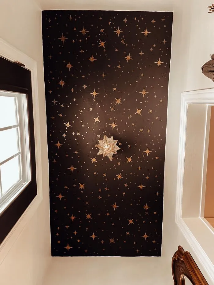 A celestial home makeover showing a dark ceiling painted with golden stars and a star lamp